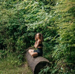 Practicing gratitude in nature with yoga while sitting on a log.