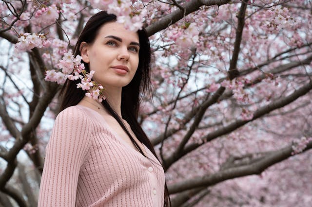 Girl staring in the distance in front of pink tree