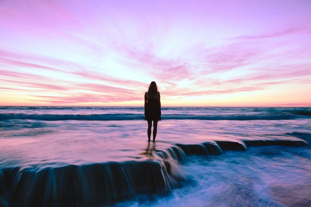 Pink skies behind lonely woman who feels left behind in life
