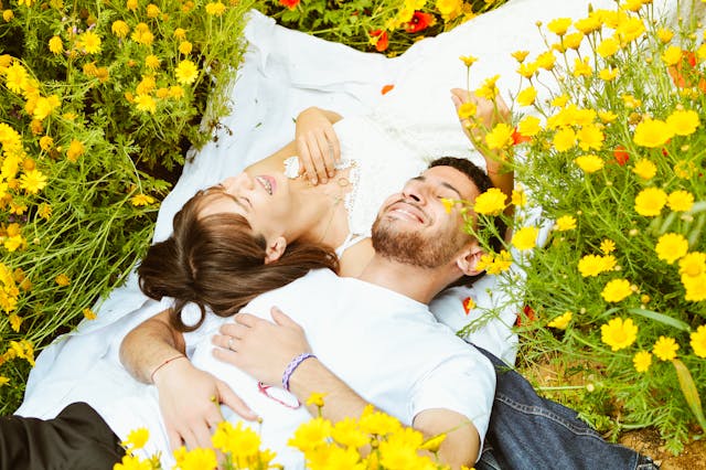 Man and woman laying in bed of flowers, showing support 