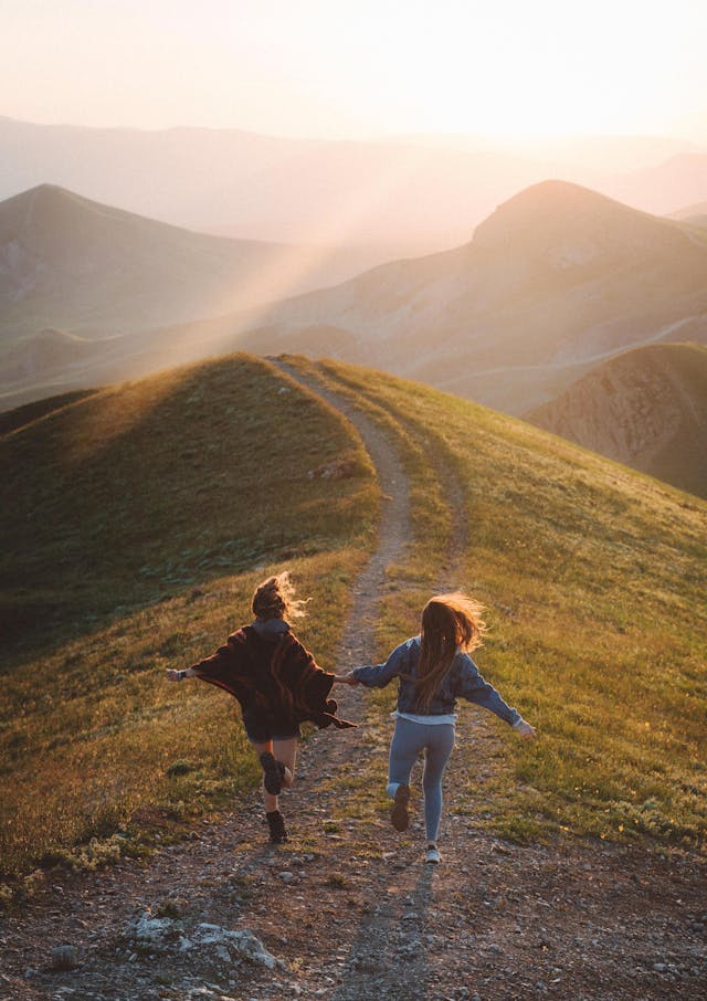 two girls with a great relationship skipping on a mountain top