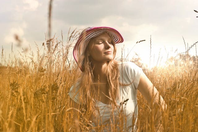 woman walking through field with high grass. She is blonde wearing a red and white hat. She is thinking about her accountability partner.