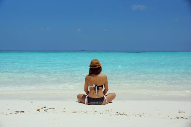 emotionally mature girl sitting on the beach looking out toward the ocean