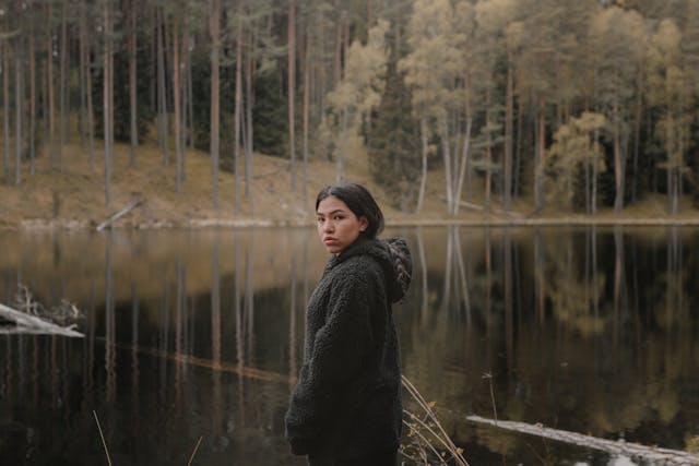 woman looking back at camera in front of lake with a fallen tree in the water
