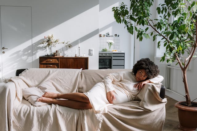 mom to be laying on a couch holding her stomach