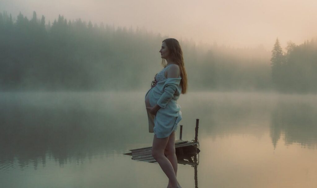 Pregnant lady standing in front of water