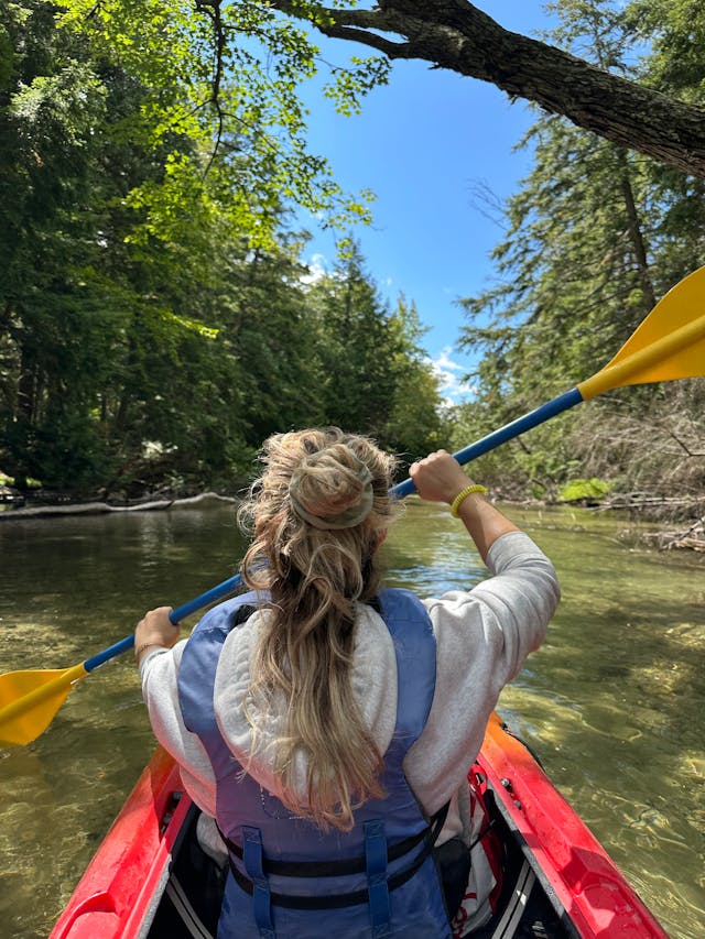 Girl kayaking down the river on sunny Summer Day.